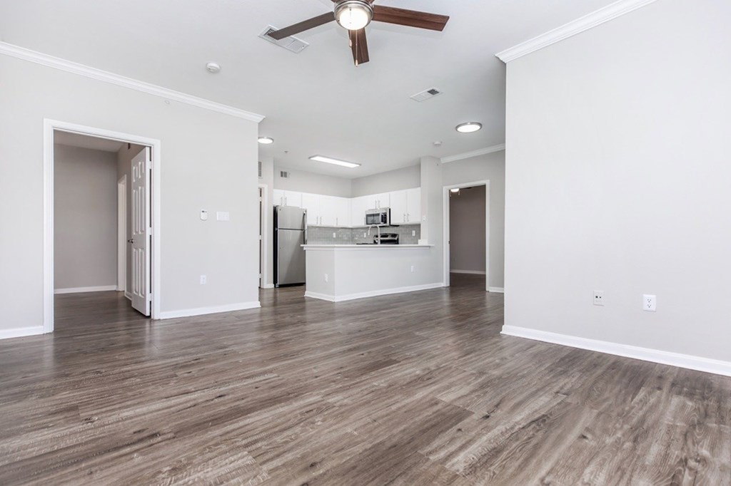 A spacious room with a ceiling fan and wooden flooring.