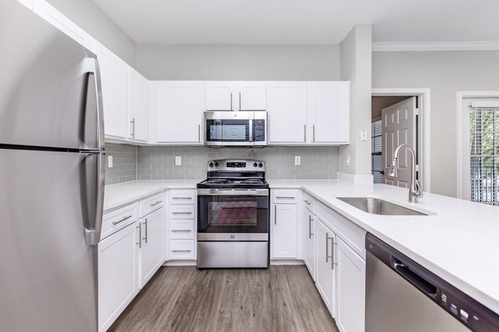 A modern kitchen with white cabinets and stainless steel appliances.