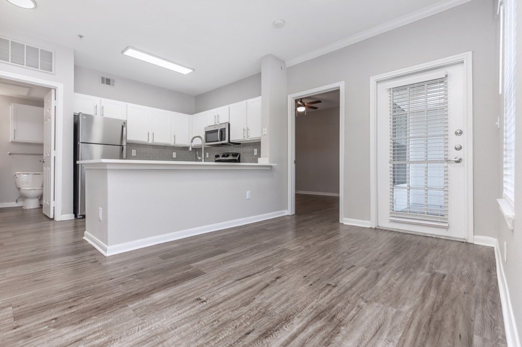 A kitchen with white cabinets and a wooden floor.