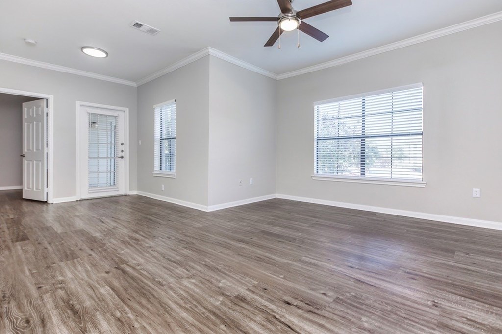 A room with a ceiling fan and wood flooring.