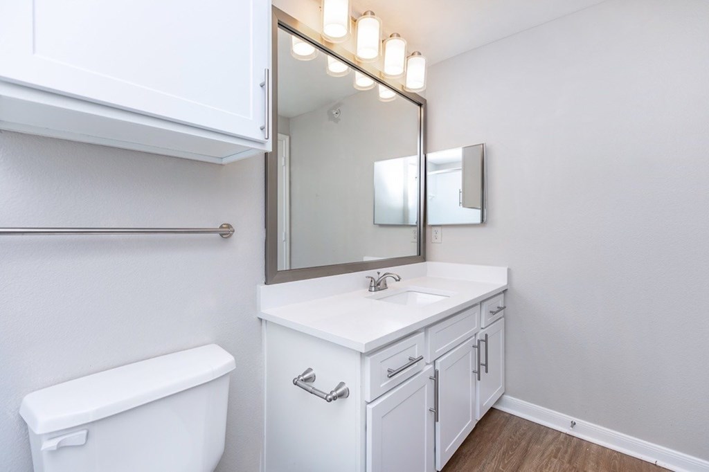 A white bathroom with a toilet, sink, and mirror.