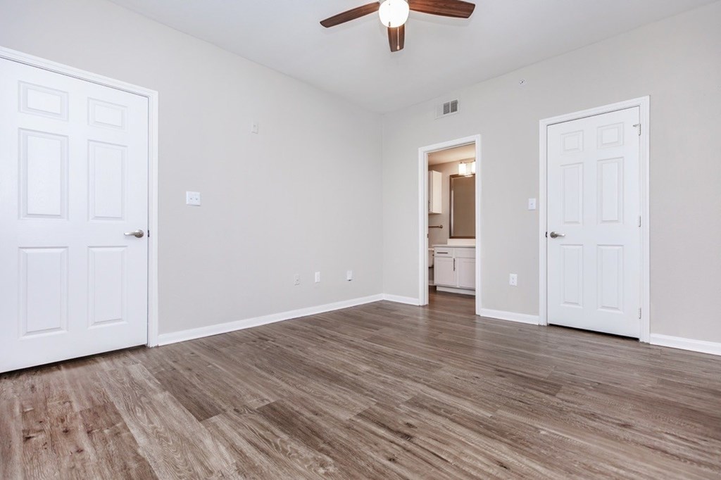 A room with a ceiling fan and wood flooring.