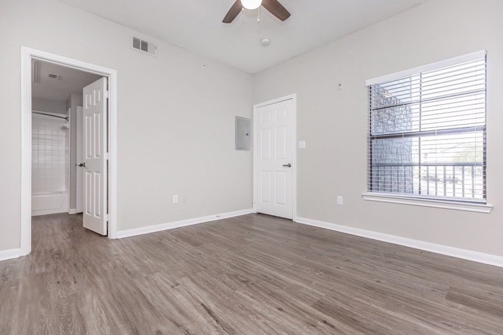 A room with a ceiling fan and a window with blinds.