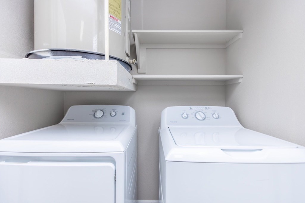 Two white washing machines in a small laundry room.