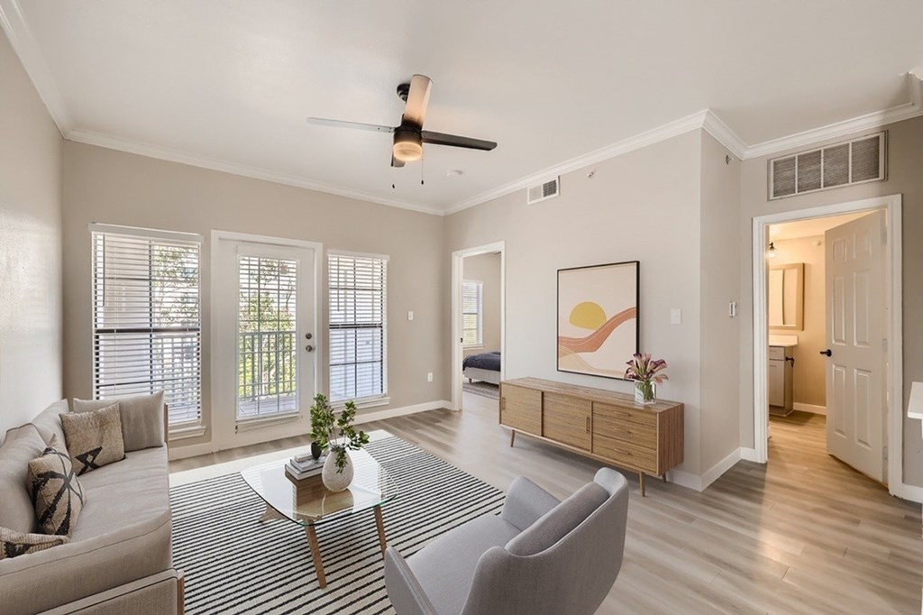 A living room with a grey couch, a coffee table, and a ceiling fan.
