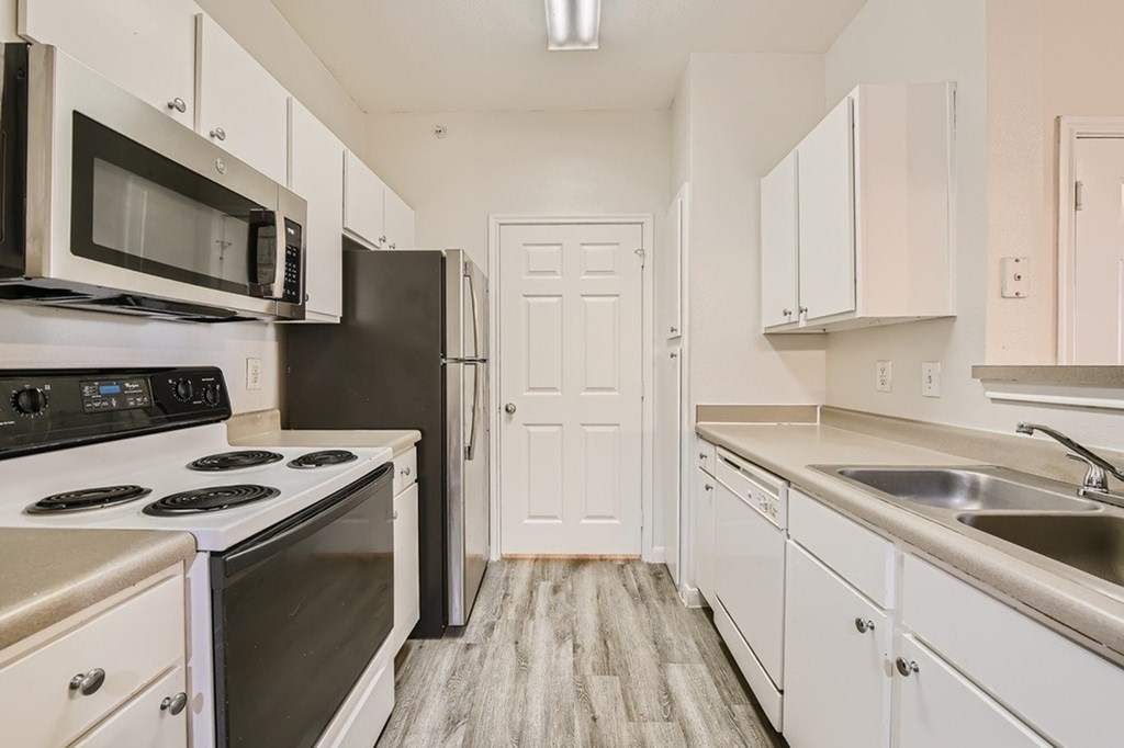 A kitchen with white cabinets and a black refrigerator.