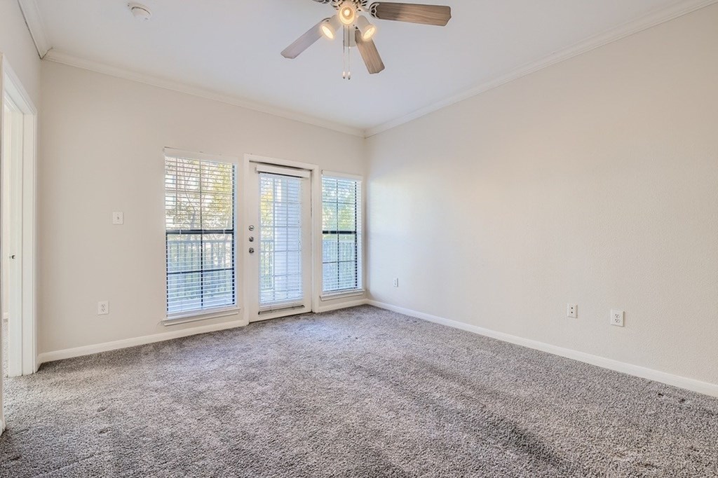 A room with a ceiling fan and carpeted floor.