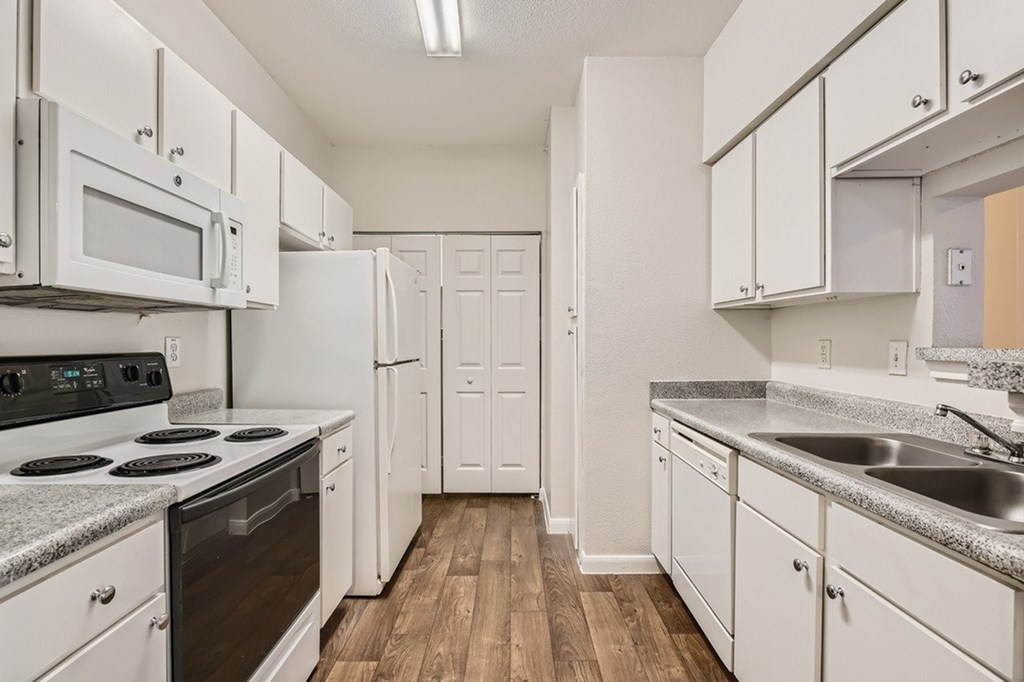 A kitchen with white cabinets and a wooden floor.