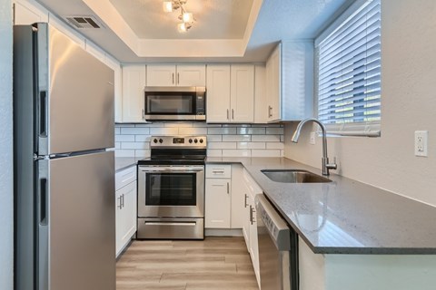 A modern kitchen with stainless steel appliances and white cabinets.
