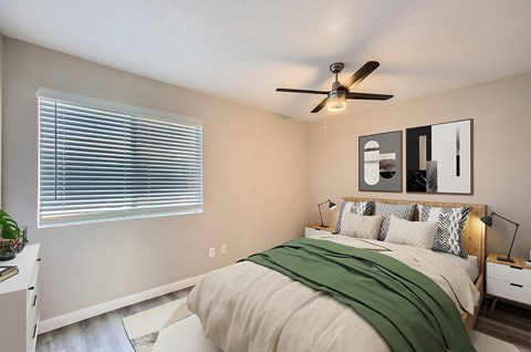 A bedroom with a bed, a ceiling fan, and a window with blinds.