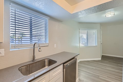 A kitchen with a sink and a window with blinds.