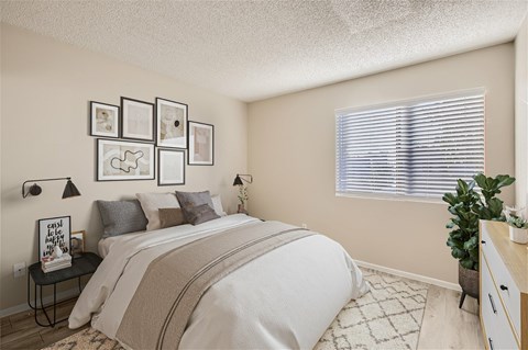 A bedroom with a large bed and a window with blinds.