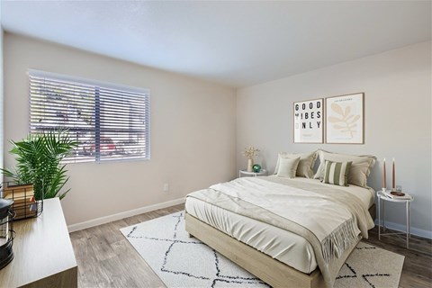 A bedroom with a large bed and a plant on the windowsill.