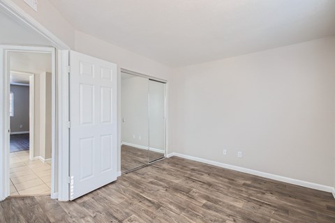 A room with a white door and wood flooring.