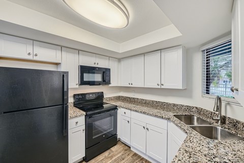 A kitchen with black appliances and white cabinets.