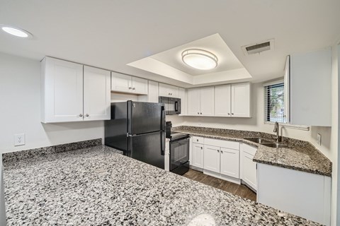 A kitchen with granite countertops and white cabinets.