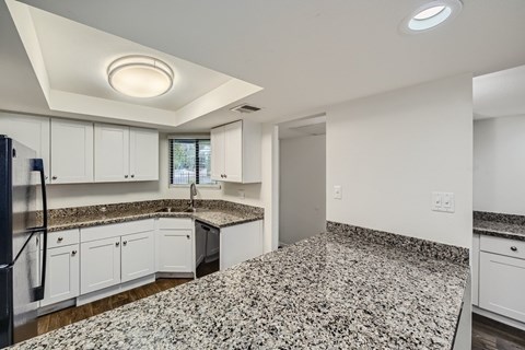 A kitchen with granite countertops and white cabinets.