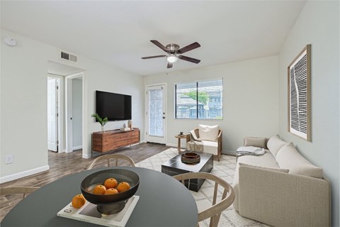 A living room with a grey table and a bowl of oranges on it.