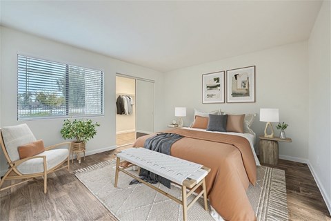 A bedroom with a bed, chair, and window.