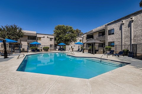 A swimming pool surrounded by a fence and umbrellas.