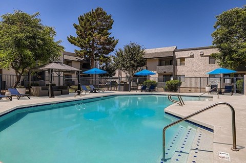 A swimming pool with a ladder and umbrellas.