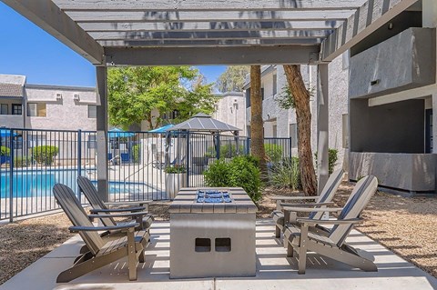 A patio area with a table, chairs and a grill.