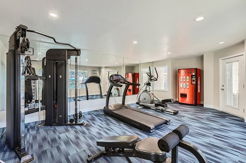 A gym with a variety of equipment including treadmills, weights, and exercise machines.