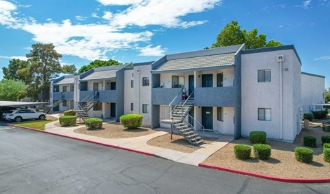 A sunny day at a residential complex with a car parked in front.