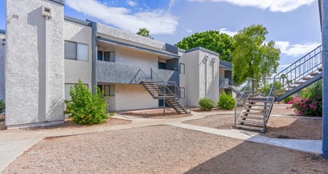 A modern house with a grey exterior and a gravel driveway.