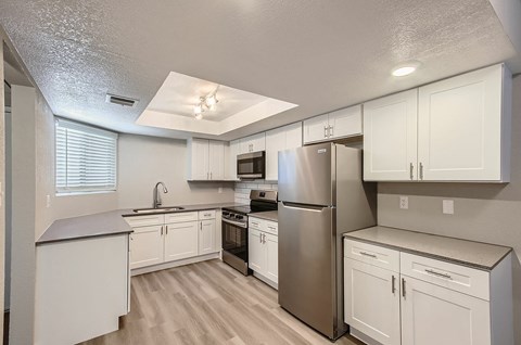 A kitchen with white cabinets and a stainless steel refrigerator.