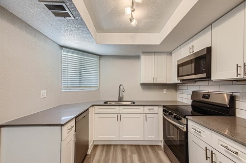 A kitchen with white cabinets and a black stove top oven.