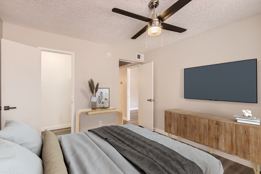 A bedroom with a bed, a ceiling fan, and a wooden cabinet.