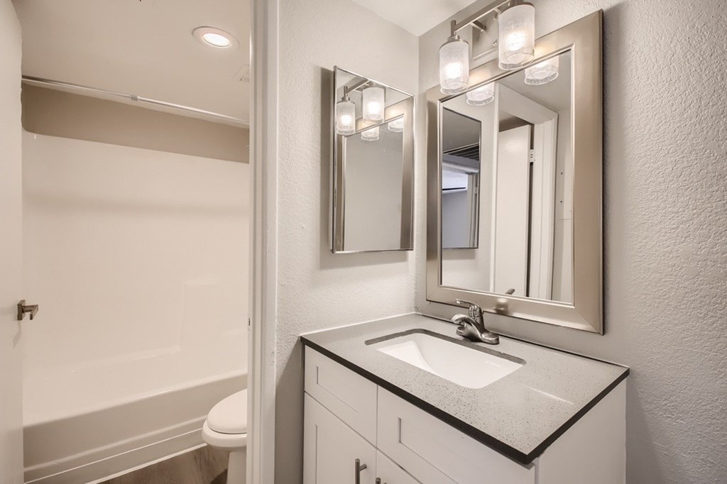 A bathroom with a sink, mirror, and toilet.
