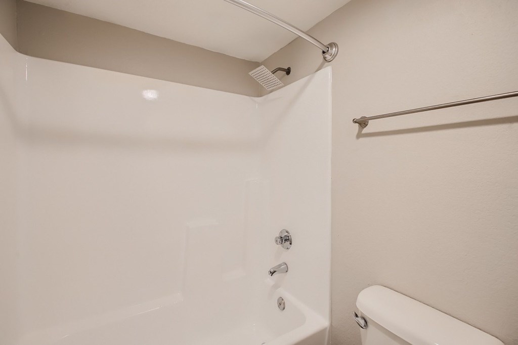 A white bathtub with a shower head and a shower curtain rod.