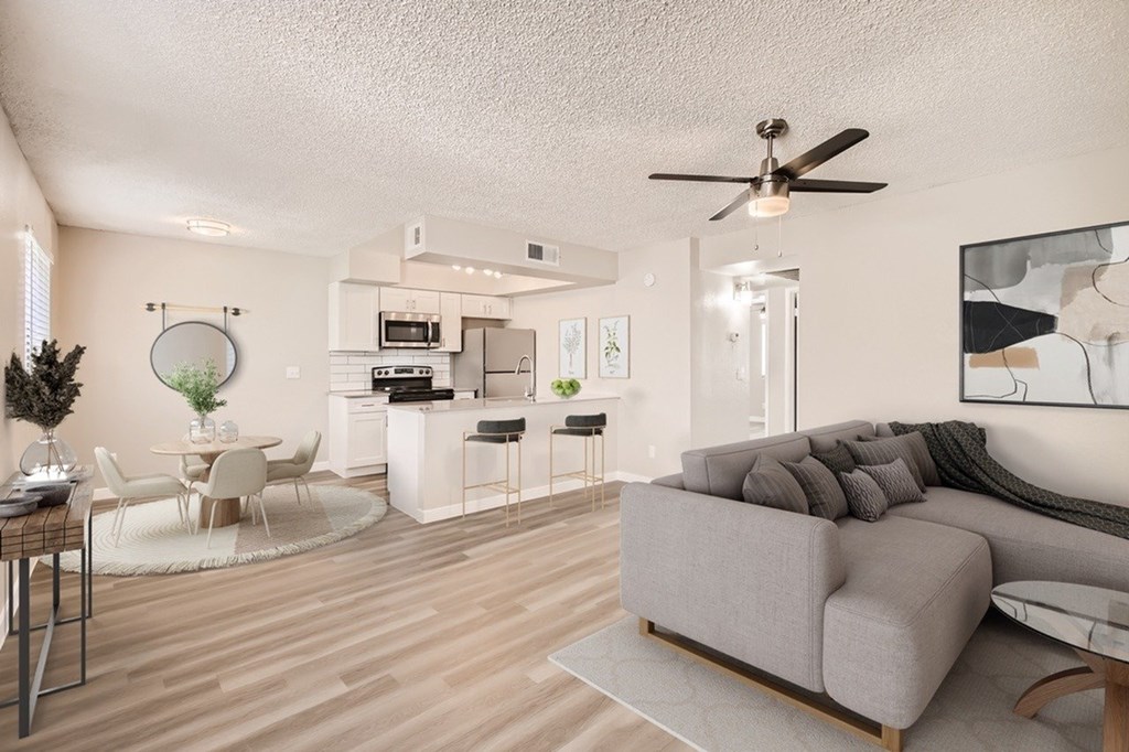 A living room with a grey couch and a white kitchen in the background.