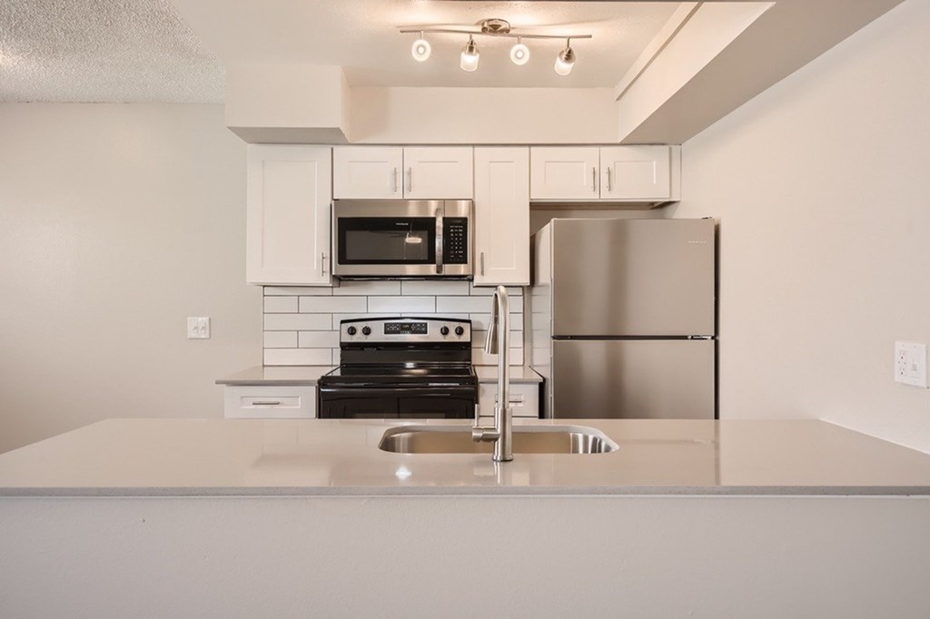 A modern kitchen with a stainless steel refrigerator, microwave, and oven.