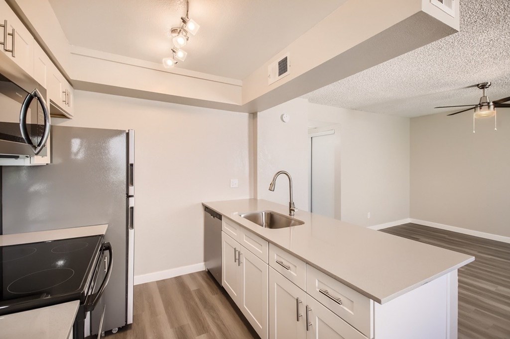 A kitchen with a black fridge and white countertops.