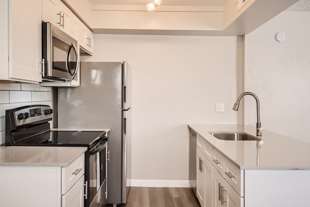 A kitchen with a black countertop and stainless steel appliances.