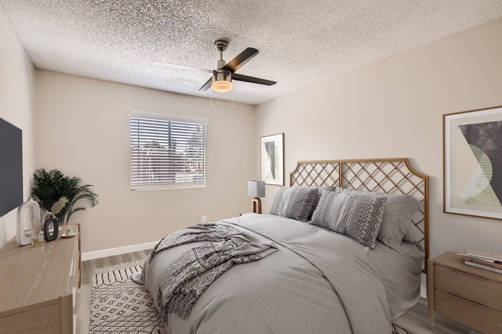 A bedroom with a bed, nightstand, and a plant.