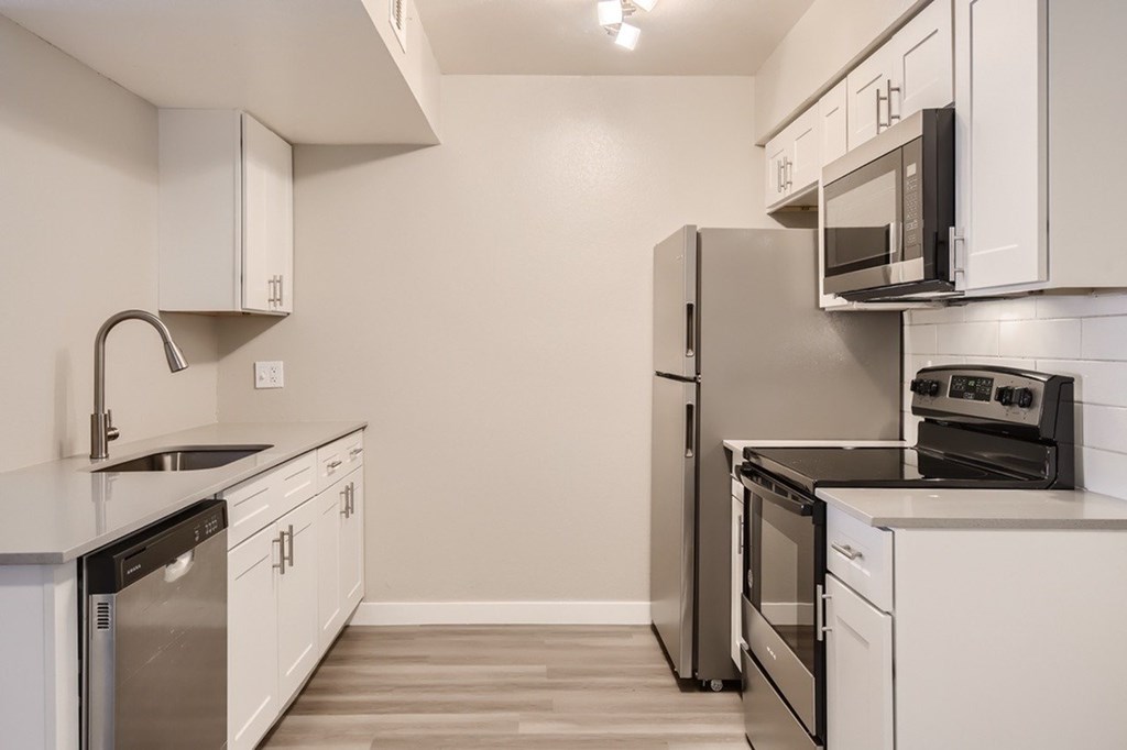 A kitchen with white cabinets and black appliances.