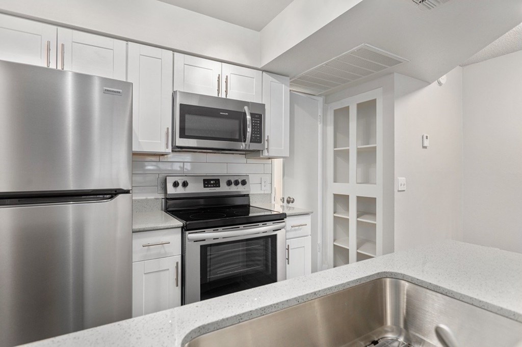 A modern kitchen with a stainless steel refrigerator, microwave, oven, and a sink.