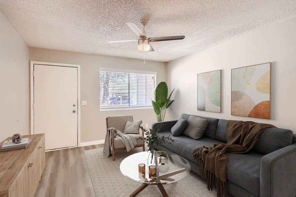 A living room with a grey couch, a coffee table, and a ceiling fan.