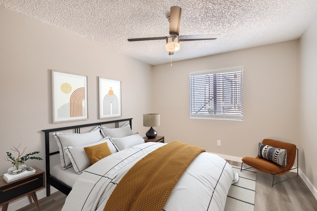 A bedroom with a bed, a chair, and two pictures on the wall.