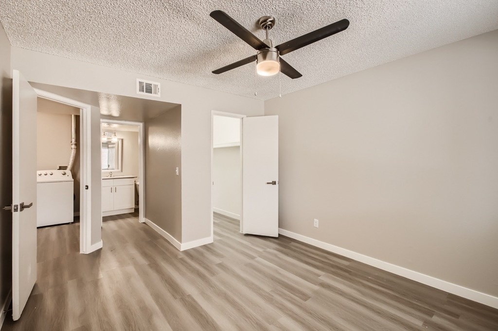 A room with a ceiling fan and light fixture, and a washer and dryer in the adjacent room.