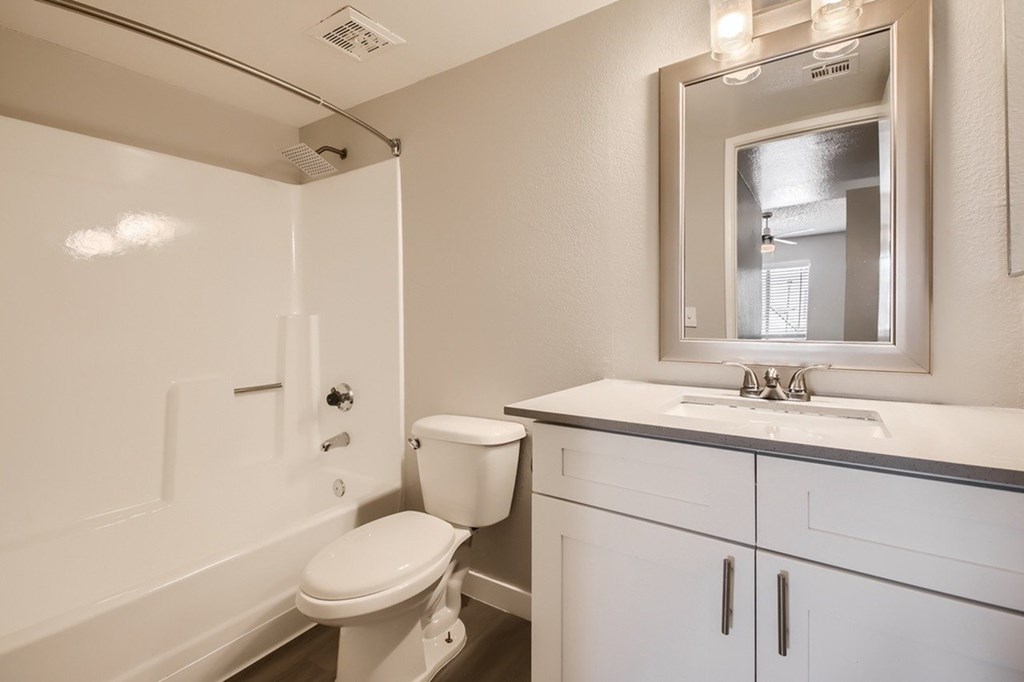 A white bathroom with a toilet, sink, and mirror.