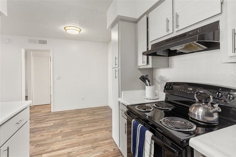 A kitchen with a black stove top oven and white cabinets.