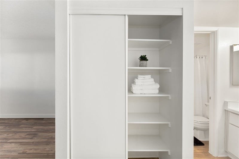 A white bathroom with a white cabinet open to the second shelf.