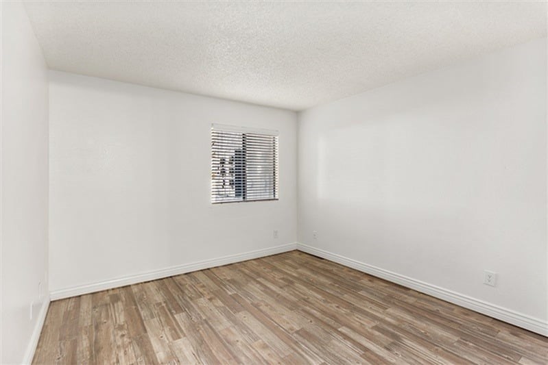 A room with wooden flooring and a window with blinds.
