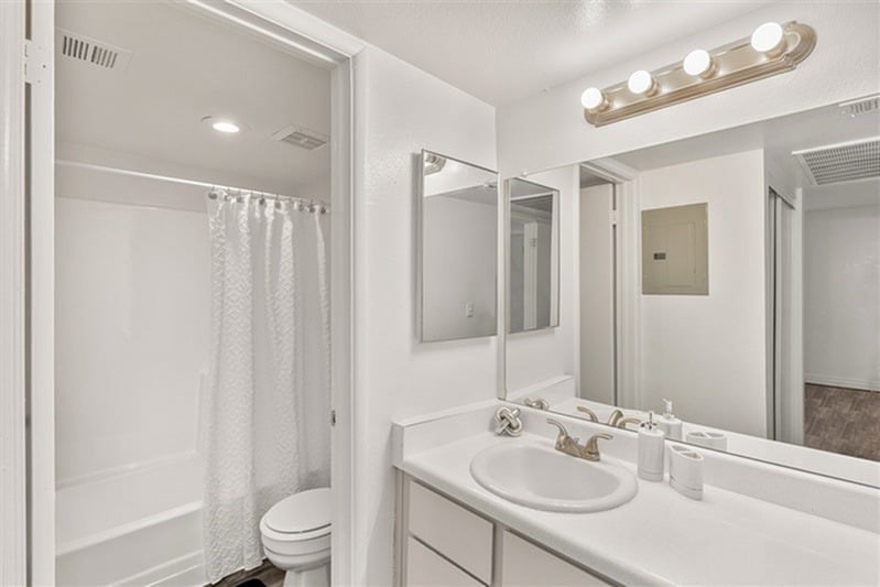 A white bathroom with a toilet, sink, and mirror.