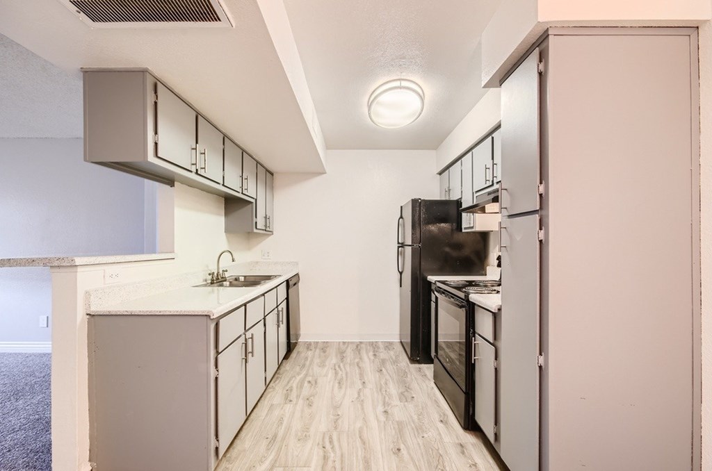 A kitchen with a sink, stove, and refrigerator.